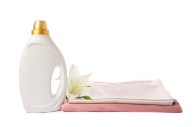 Bir şişe yumuşatıcı, üst üste yığılmış giysiler ve beyaz bir çiçek.
