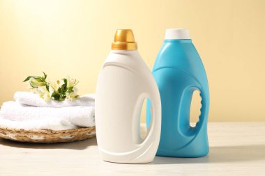 Beyaz ahşap masada açık sarı arka plana karşı yumuşatıcı, terry havlu ve zambak çiçekleri.