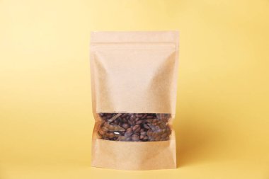 Açık turuncu arka planda kahve çekirdekleri olan fermuarlı bir stand-up kesesi. Tasarım için model