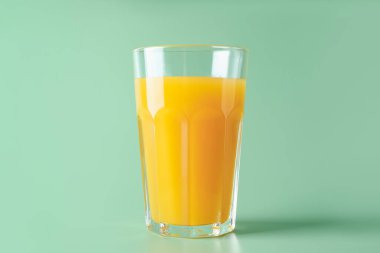 Yeşil arka planda cam içinde lezzetli mango suyu.