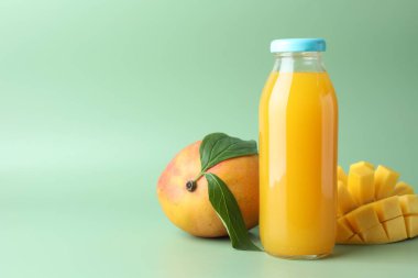 Cam şişede lezzetli mango suyu ve yeşil arka planda taze meyve, mesaj için yer var.