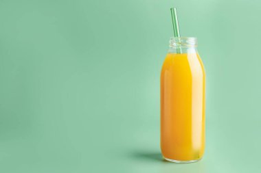 Yeşil arka planda cam şişede lezzetli mango suyu, mesaj için yer