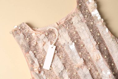 Bej arka planda etiketli şık elbise, üst görünüm