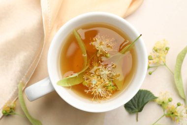 Taze ıhlamur çayı fincanda ve çiçekler beyaz masada, düz yerde.