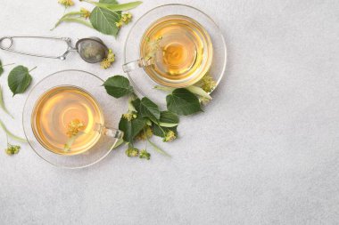 Taze ıhlamur çayı fincanda ve çiçekler açık gri masada, düz yerde. Metin için boşluk