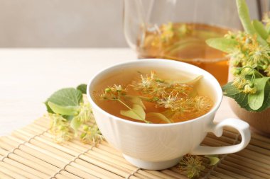 Taze ıhlamur çayı, çaydanlık ve çiçekler beyaz masada, yakın plan. Metin için boşluk