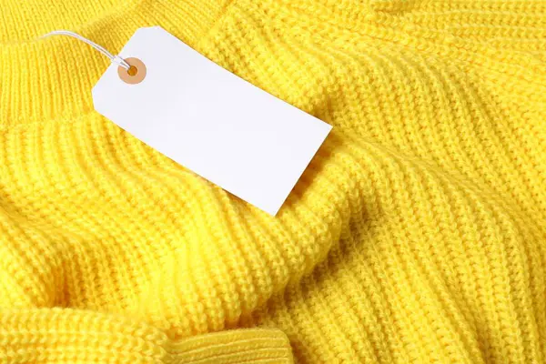 Sarı örülmüş süveterin üzerindeki karton etiket.
