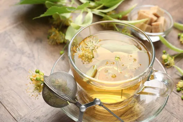 Taze ıhlamur çayı, şeker küpleri ve çiçekler ahşap masada, yakın plan.