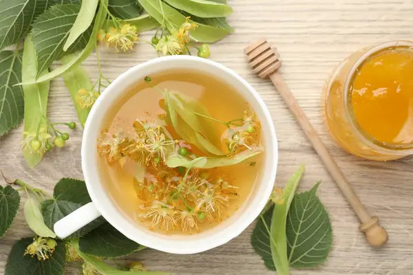 Taze ıhlamur çayı fincanda, bal ve çiçekler ahşap masada, düz yerde