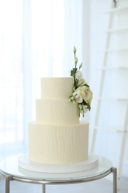 İçerideki masada çiçeklerle süslenmiş nefis düğün pastası.