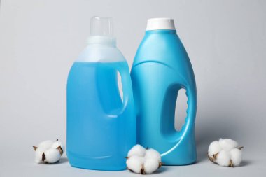 Kumaş yumuşatıcı şişeler ve açık gri arkaplanda pamuk çiçekleri