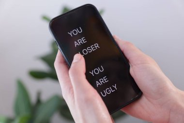 Siber zorbalık. Bulanık arkaplanda akıllı telefon tutan kadın, yakın plan.