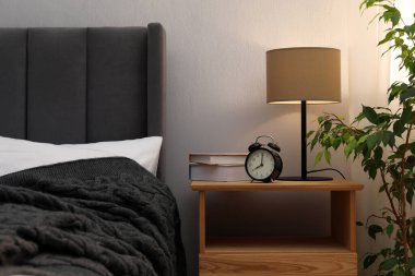 İçinde lamba, çalar saat ve yatağın yanında kitaplar olan komodin. İç tasarım