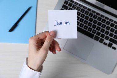 Elinde kağıt notlar tutan bir kadın. Açık tahta masada bize katıl.