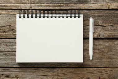 Defter ve kalem ahşap masada, düz yatıyordu.