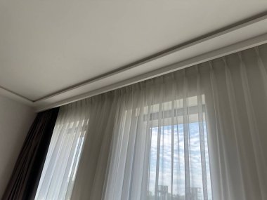 Güzel perdeler pencerenin yanında asılı, alçak açılı manzara.