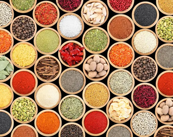 Siyah arka plandaki kaselerde farklı aromatik baharatlar dizisi.