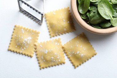 Pişmemiş ravioli, keski ve ıspanak beyaz masada, düz yerde.