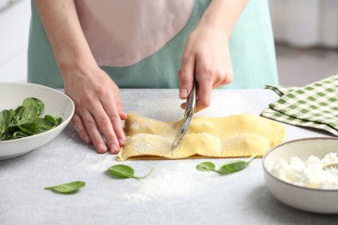 Işık masasında ravioli kesen kadın, yakın plan.