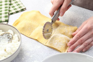 Işık masasında ravioli kesen kadın, yakın plan.
