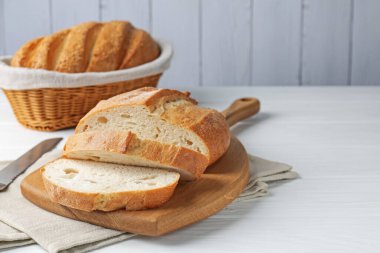 Beyaz ahşap masada ekmek somunu ve bıçak kes, yakın plan. Metin için boşluk