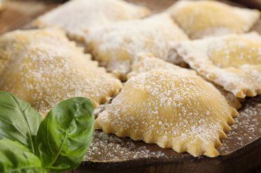 Ahşap masada pişmemiş ravioli ve fesleğen, yakın plan.