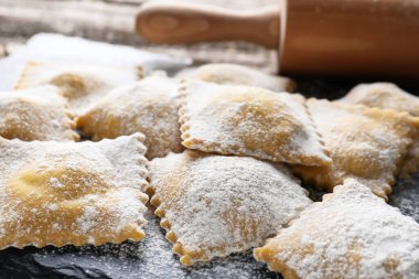 Pişmemiş ravioli ve merdane ahşap masada, yakın plan.