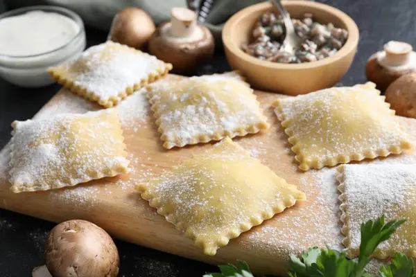 Pişmemiş ravioli, mantar ve sos siyah masada, yakın plan.