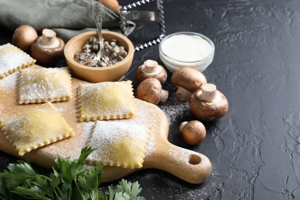 Pişmemiş ravioli, mantar ve sos siyah masada, yakın plan.