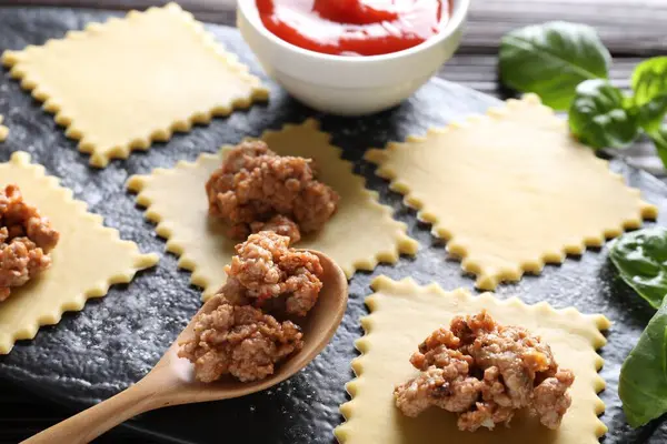 Ahşap masada ravioli bolonez yapıyorum, yakın plan.