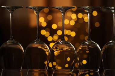 Bulanık ışıklara karşı cam ayna yüzeyinde birçok temiz bardak, yakın plan. Bokeh etkisi