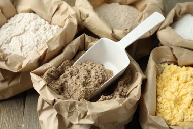 Tahta masadaki kağıt torbalarda farklı türde un, yakın plan.