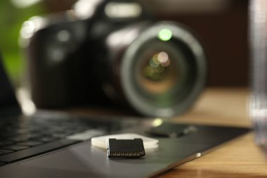 SD hafıza kartları, tutucu, dizüstü bilgisayar ve fotoğraf makinesi ahşap masada, yakın plan.