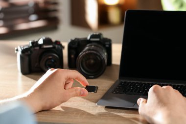 SD bellek kartını bilgisayarın içine yerleştiren adam ahşap masa, yakın plan