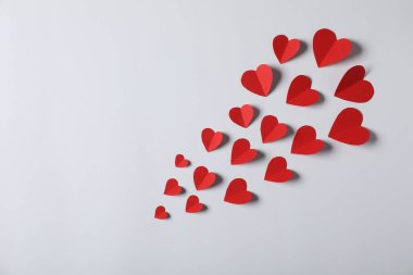 Açık gri arkaplanda bir sürü kağıt kalp, düz bir zemin. Metin için boşluk
