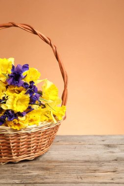 Mercan zeminine karşı ahşap masanın üzerinde güzel çiçekler olan hasır sepet. Metin için boşluk