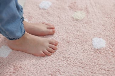 Evdeki yumuşak halıdaki kız, yakın plan.