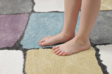 Evdeki yumuşak halıdaki kız, yakın plan.