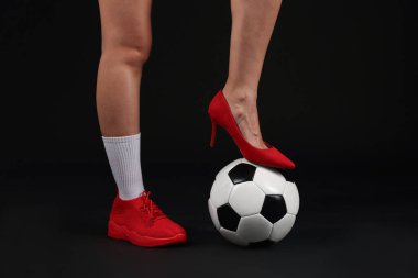 Arka planda futbol topu olan yüksek topuklu ayakkabılı ve spor ayakkabılı bir kadın.