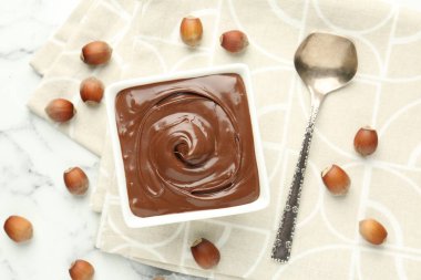 Lezzetli çikolata ve fındıklar beyaz masada, düz yerde.