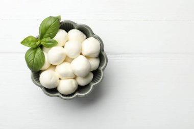 Beyaz ahşap masada mozzarella peynirli toplar ve fesleğen. Metin için boşluk