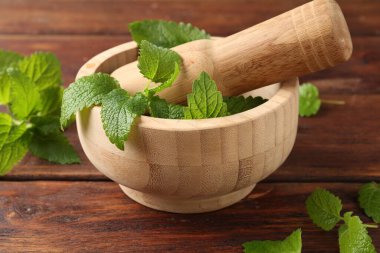 Taze limon merhemi yaprakları, ahşap masada tokmak ve havan topu, yakın plan.