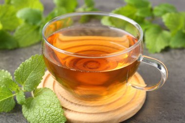 Cam bardakta Aromatik limon merhemi çayı ve gri masada taze yapraklar, yakın plan.