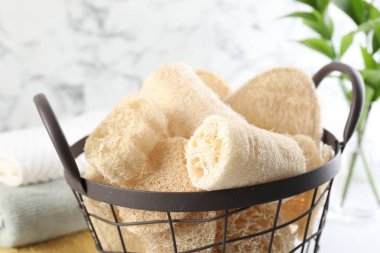 Sepette farklı lif süngeri ve masa üzerinde havlular, yakın plan.