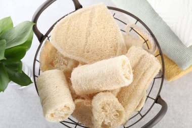 Sepette farklı lif süngerleri ve açık gri masa üzerinde havlular.