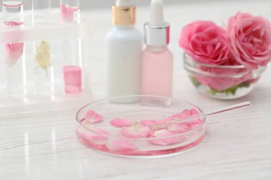 Lüks parfüm yapıyorum. Temel yağlar cam süslemede ve çiçekler beyaz ahşap masada, yakın plan.