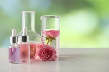 Lüks parfüm yapıyorum. Temel yağlar cam kaplama ve çiçekler beyaz ahşap masa üzerinde bulanık arka plan, yakın çekim. Metin için boşluk