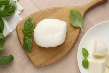 Ahşap masada mozzarella peyniri ve fesleğen var.