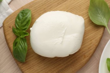 Ahşap masada mozzarella peyniri ve fesleğen var.
