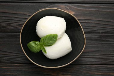 Lezzetli mozzarella peyniri ve fesleğen parçaları ahşap masada, üst tarafta.